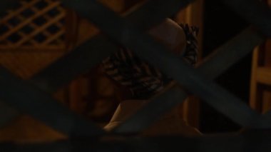 A Muslim Boy sitting in front of the bamboo pattern wall inside the traditional bamboo house at night with the flame light
