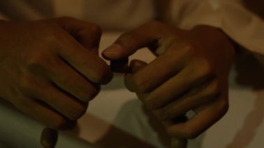 A Hands holding prayer beads while a Muslim man praying inside the traditional house at the night