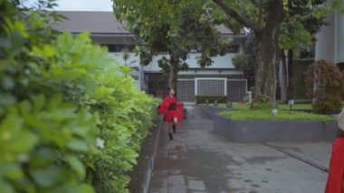 Chinese kids with red costume playing in the garden inside the temple