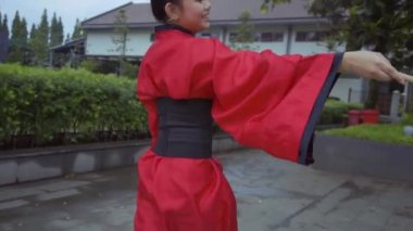 A Chinese Kids in a red costume having fun while playing with the rope inside the temple