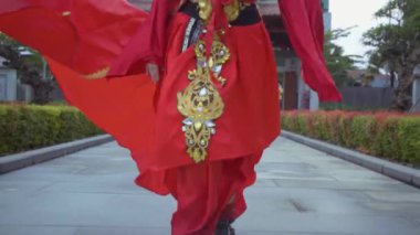 A beautiful Chinese woman running in the red costume inside the garden at the China Town