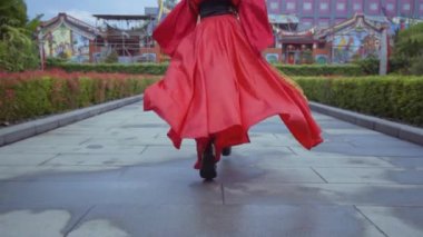 A beautiful Chinese woman running in the red costume inside the garden at the China Town