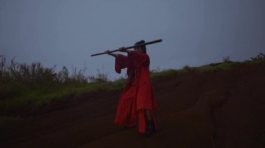 Asian women performing wooden martial art in the mountain while wearing red costumes in the dark morning