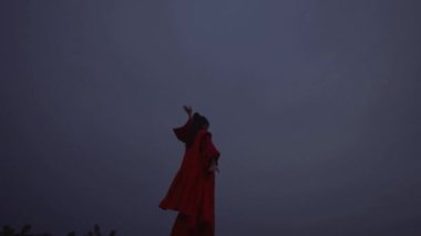 A Chinese woman doing body movements on the hill during the dark morning on the outdoor