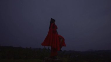 A Chinese Woman doing a meditation movement during the morning with the cloud in the background