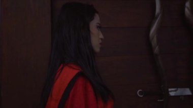 Chinese Woman taking the silver sword on the brown door inside the Chinese Temple
