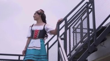 A Beautiful servant girl down the stairs with confidence while wearing a blue skirt in the daylight