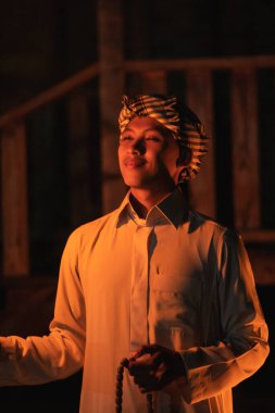 Gece karanlığında Müslüman elbisesi giyen ve köyde yanan bir meşale taşıyan bir adam.