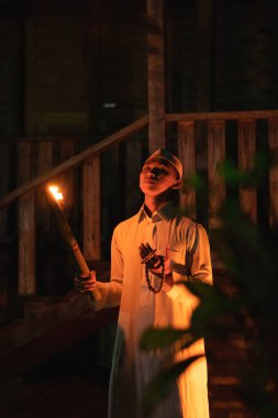 Elinde meşale olan Müslüman bir adam köyün önünde kamp alanının içinde duruyordu.