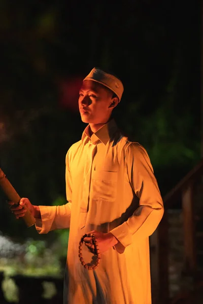 A Muslim man lighten up the campsite with the fire torch in his hands during the dark night