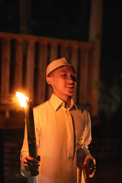 A Muslim man holding a fire torch at the campsite in the village in the dark night