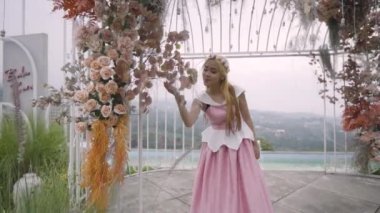 Bahçedeki kafeste pembe elbiseli bir prenses oynarken bahçedeki çiçekler onu sarıyordu.