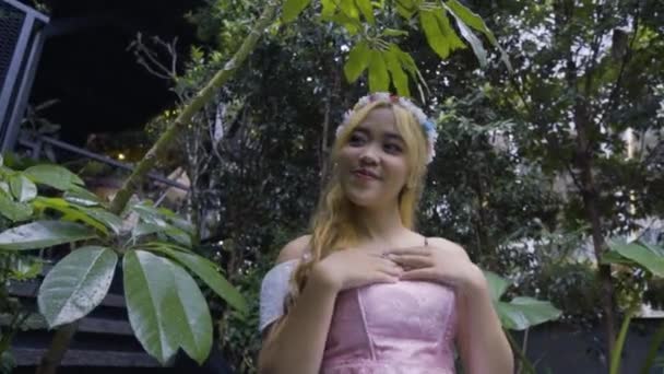 一位金发公主 穿着粉色衣服在森林城堡里玩耍 身边长满了绿叶和花朵 — 图库视频影像