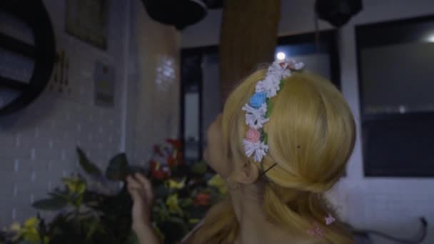 一位亚洲公主穿着一件婚纱坐在小花园里 手上拿着鲜花和鸟巢 — 图库视频影像