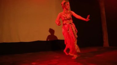 Gecenin karanlığında sahne ışığıyla dans ederken geleneksel bir kostüm giyen bir Java dansçısı.