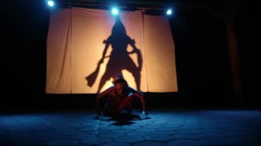 Bir Siluet dansçısı ışık sahnesinde dans ederken kadın dansçıya eşlik eder.