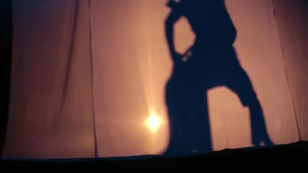 舞台照明と暗い夜に一緒に彼女の後ろの女性と一緒に踊る男シルエット — ストック動画