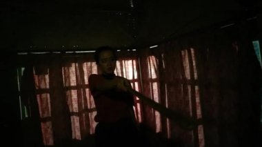 Karanlık odanın siluetleriyle karanlık pencerenin önünde dans eden Asyalı kadınlar.