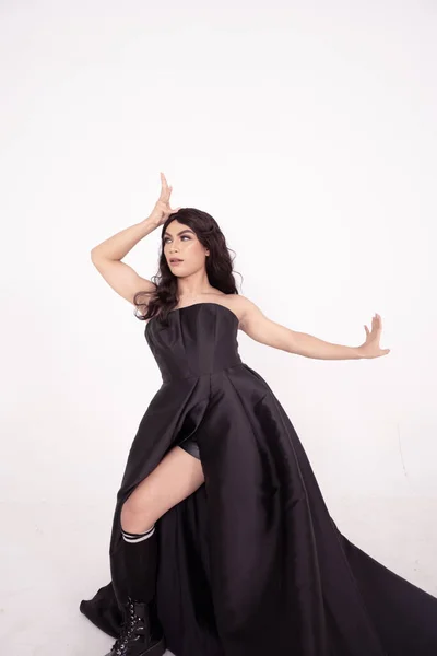 A whole body of an Asian woman in a black dress poses in a white studio with dark brown hair
