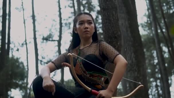 弓と矢を持つ女射手黒の衣装を着ている間 彼女は怒っている式を持つ敵のためのジャングル狩り — ストック動画