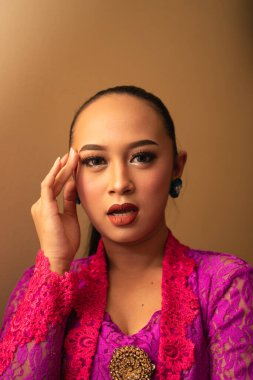 Stüdyoda makyajla poz verirken Asyalı kadın kafasına dokunuyor.