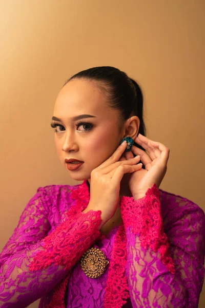 Azjatka Różowej Sukience Próbuje Nosić Zielony Kolczyk Uszach Wewnątrz Studia — Zdjęcie stockowe