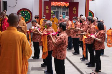 Bandung, Endonezya - 8 Ocak 2022: Turist Çin kasabasındaki Buda tapınağında tanrıya dua ederken rahipler için adak getirir.