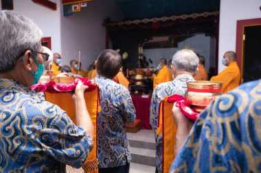 Bandung, Endonezya - 8 Ocak 2022 Budist halkı, Buda tapınağının sunağı önünde sunum yaparken rahiplerle birlikte dua ediyor.