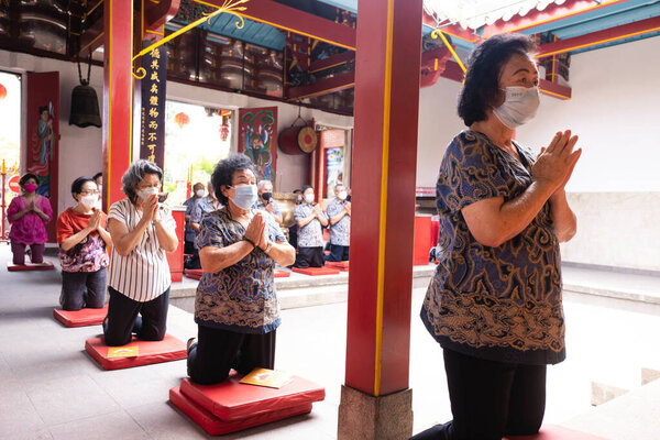 Bandung, Indonesia - January 8, 2022 : Buddhist People pray together with the monks while giving the offering in front of the altar inside the Buddha temple