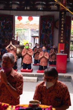 Bandung, Endonezya - 8 Ocak 2022: Budist toplumu tapınağın içindeki rahiplerle mihrapta dua ederken birlikte sandalyede oturuyor