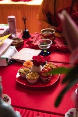 Bandung, Endonezya - 8 Ocak 2022: Buda tapınağının içindeki keşişlerin duaları sırasında kırmızı Budist masasının tepesindeki yemek ve mum gibi kurbanlar