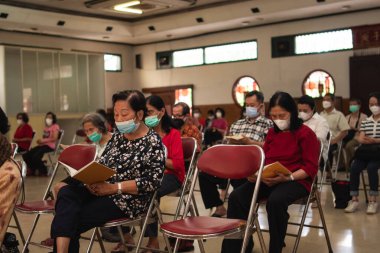 Bandung, Endonezya - 8 Ocak 2022: Budist toplumu tapınağın içindeki rahiplerle mihrapta dua ederken birlikte sandalyede oturuyor