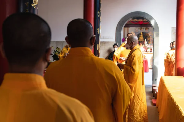 2022年1月8日 2022年1月8日 インドネシア バンドン 中国の町にある仏寺内の祭壇で神に祈願しながらオレンジの衣を着た僧侶が立ち上がる — ストック写真