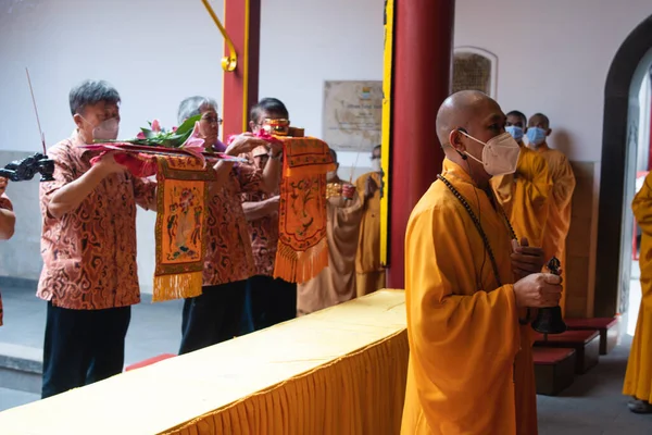 2022年1月8日 2022年1月8日 インドネシア バンドン 中国の町にある仏寺内の祭壇で神に祈願しながらオレンジの衣を着た僧侶が立ち上がる — ストック写真