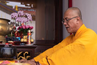 Bandung, Endonezya - 8 Ocak 2022: Tapınağın içinde turuncu kostümlerle sunakta dua eden rahipler