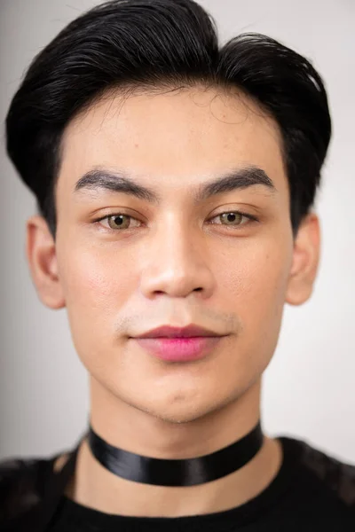 Asian man with a pretty face wearing a black costume while posing inside the white room at the studio