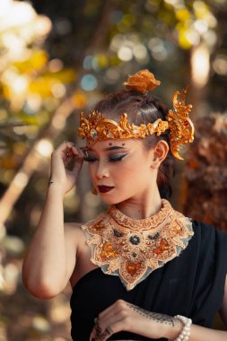 Kabile kraliçesi altın bir taç ve altın bir kolye takarken ormanın içinde siyah elbisesi vardı.