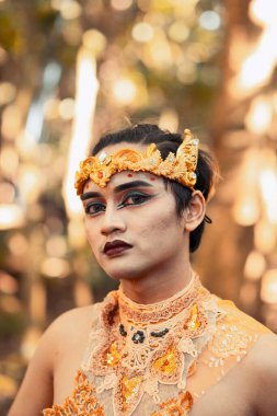 Siyah göz farı takan Asyalı erkekler ve köyün içinde kafasına altın bir taç takarken yüzünde kırmızı siyah dudaklar vardı.