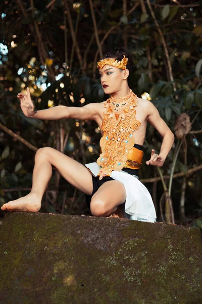亚洲人身穿金色服装 头戴金色王冠 坐在森林里的大岩石顶上 跪在地上 — 图库照片