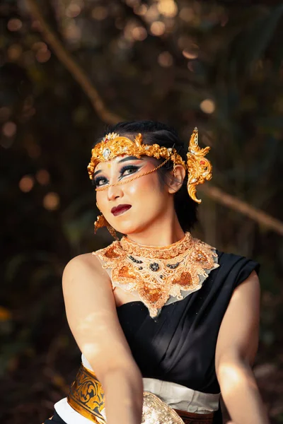 一名头戴金色王冠 身穿黑色服装的爪哇妇女在村里化妆时在森林里浑身冰冷 — 图库照片