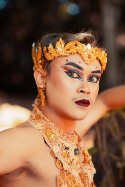 Yüzüne altın bir taç ve ormanda üstsüz altın bir kolye takmış güzel bir Cava 'lı.