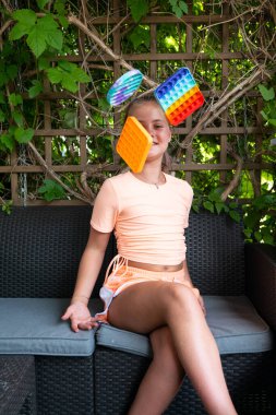 Pop it oyuncağı ya da masa oyunu oynayan, motor becerilerini geliştiren parmaklarıyla baloncuklara bastıran, stres karşıtı popüler pop oyuncağı olan bir kız. Konsantrasyon, zihinsel sorunlar konsepti. Seçici odak