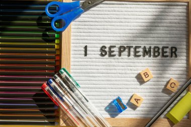 1 Eylül 'de okul malzemelerini kalem, makas, ABC ve sarı arka planda boya olarak içeren bir pano. Eğitim. Bilgi günü, ders çalışma, okul konseptine dönüş.