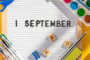 1 Eylül 'de okul malzemelerini kalem, makas, ABC ve sarı arka planda boya olarak içeren bir pano. Eğitim. Bilgi günü, ders çalışma, okul konseptine dönüş.