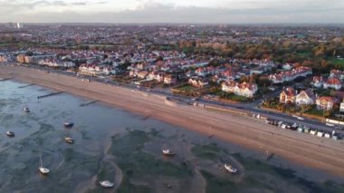 Essex, Londra 'nın kuzeyindeki bir sahil kenti olan Southend üzerinde deniz manzarası alçak gelgitte tekneleri gösteriyor. Arka planda sahil ve kasaba var. İHA kuşları bir sonbahar akşamında altın ışığa bakıyor.