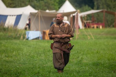 Viking adam Belçika 'daki tarihi canlandırma sırasında çadırların önünde yürüyor.