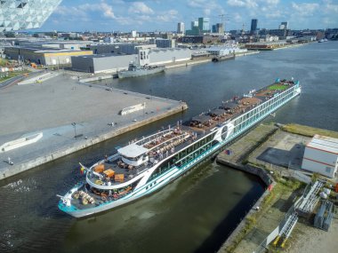 Antwerp limanında, Antwerp 'in Otorite binası yakınlarındaki Zaha Hadid bataklığında, arka planda Antwerp silueti olan bir yolcu gemisi.