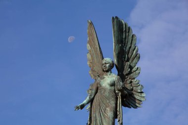 Somerset, Bath 'daki Parade Gardens' da melek heykeli. Ay ve bulutlar kadın melek kanatlarının yanında