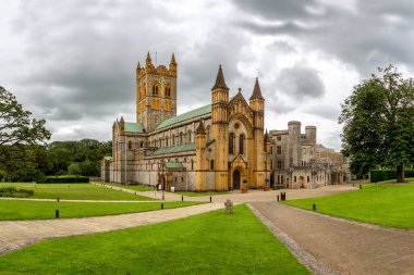 Buckfast Abbey an active Benedictine monastery at Buckfast, near Buckfastleigh, Devon, England with dramatic clouds and vibrant green grass