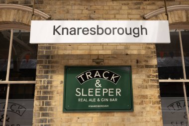 Green tea and coffee served here sign hanging on a wall and white knaresborough sign hanging at railway station North Yorkshire, UK